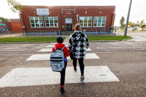 Ethan Minski, 7, walks to school for his first day of Grade 2 with his mom Christy Smolik at Prince Edward School on Wednesday morning. (Mike Deal / Free Press)