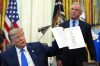 FILE - President Donald Trump holds up an image taken from his Truth Social account as Health and Human Services Secretary Robert F. Kennedy Jr. watches during a meeting to sign an executive order about vaccines, Monday, Aug. 10, 2026, in the Oval Office of the White House in Washington. (AP Photo/Jacquelyn Martin, File)