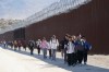 FILE - A group of people, including many from China, walk along the wall after crossing the border with Mexico to seek asylum, Oct. 24, 2023, near Jacumba, Calif. (AP Photo/Gregory Bull, File)