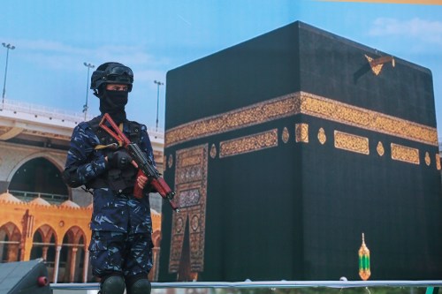 A soldier from Yemen's Houthi rebels stands in front of a giant banner of the Kaaba, during a rally to protest Saudi Arabia's accusation that the Houthis targeted Islam's holiest site in Sanaa, Yemen, Friday, Sept. 18, 2026. (AP Photo/Osamah Abdulrahman)