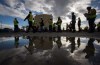 Reporters and camera operators are reflected in a puddle while walking past a storage tank during a tour of FortisBC's Tilbury LNG facility in Delta, B.C., on Tuesday Oct. 21, 2014. THE CANADIAN PRESS/Darryl Dyck