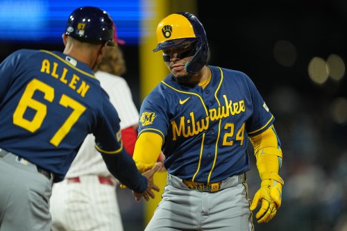 Milwaukee Brewers' William Contreras celebrates his hits a two-run single off of Philadelphia Phillies pitcher Aaron Nola with teammate first base coach Spencer Allen during the third inning of a baseball game, Wednesday, Sept. 23, 2026, in Philadelphia. (AP Photo/Matt Rourke)