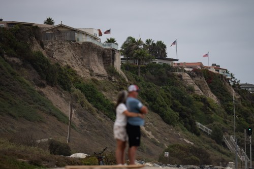 A couple hug at North Beach as crumbling seaside bluffs are seen behind them in San Clemente, Calif., Friday, Sept. 18, 2026. (AP Photo/Jae C. Hong)