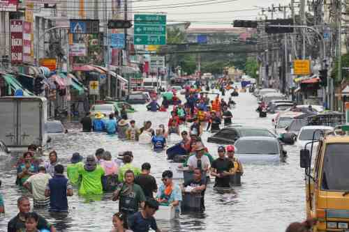 People wade through a flooded street after heavy rain in Bangkok, Thailand, Monday, Sept. 28, 2026. (AP Photo/Sakchai Lalit)
