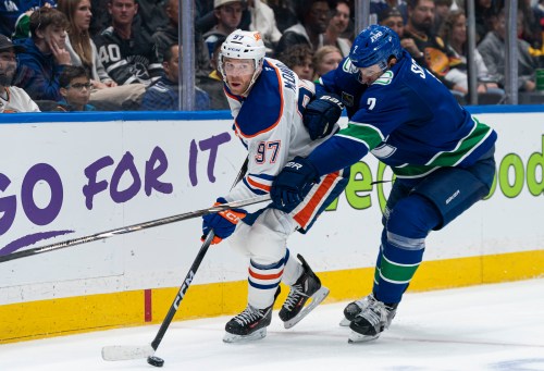 Vancouver Canucks' Luke Schenn (2) tries to check Edmonton Oilers' Connor McDavid (97) during second period NHL hockey action in Vancouver, B.C., on Thursday, Oct. 1, 2026. THE CANADIAN PRESS/Rich Lam