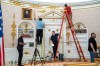 A replica of President Donald Trump's Oval Office is updated to the current decor by workers at 