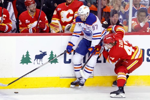 Edmonton Oilers' Connor McDavid, left, battles for the puck against Calgary Flames' Connor Zary during second-period NHL hockey action in Calgary, Wednesday, Feb. 4, 2026. THE CANADIAN PRESS/Larry MacDougal