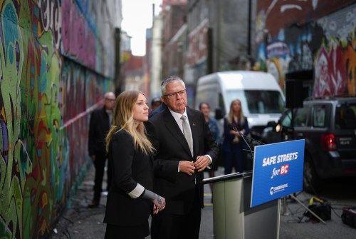 B.C. Conservative interim Leader Lorne Doerkson and Skeena Conservative candidate Claire Rattee, left, listen during a provincial election campaign announcement in an alley in downtown Vancouver, on Tuesday, Oct. 6, 2026. THE CANADIAN PRESS/Darryl Dyck