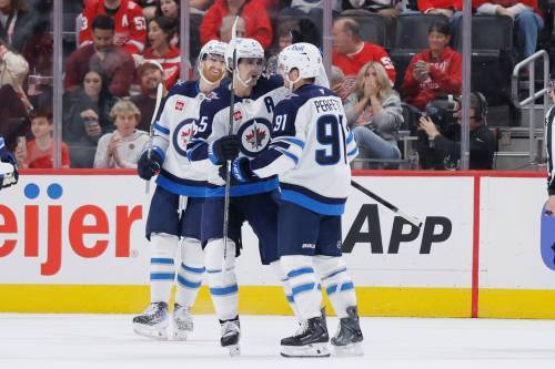 Winnipeg Jets center Cole Perfetti (91) celebrates after his goal against the Detroit Red Wings with left wing Kyle Connor, left, and center Mark Scheifele (55) during the first period of an NHL hockey game Sunday, Oct. 4, 2026, in Detroit. (Duane Burleson / The Associated Press)