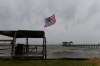 An American flag flaps in the wind generated by the effects of Isaias on an empty beach on Friday, Oct. 9, loom overhead on Friday, Oct. 9, 2026, in Mon Louis Island, Ala. (AP Photo/Octavio Jones)