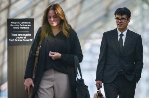 Author and former University of British Columbia professor Steven Galloway, back right, and his wife Katie Wagner are seen through a window as they leave B.C. Supreme Court during a lunch break at his defamation lawsuit, in Vancouver, on Tuesday, Oct. 6, 2026. THE CANADIAN PRESS/Darryl Dyck