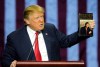 FILE - Then-Republican presidential candidate Donald Trump holds up his book 