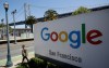 FILE - In this May 1, 2019, file photo a man walks past a Google sign outside with a span of the Bay Bridge at rear in San Francisco. (AP Photo/Jeff Chiu, File)